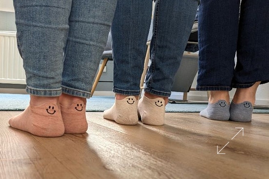 Das Praxisteam zeigt Socken mit Smileys.